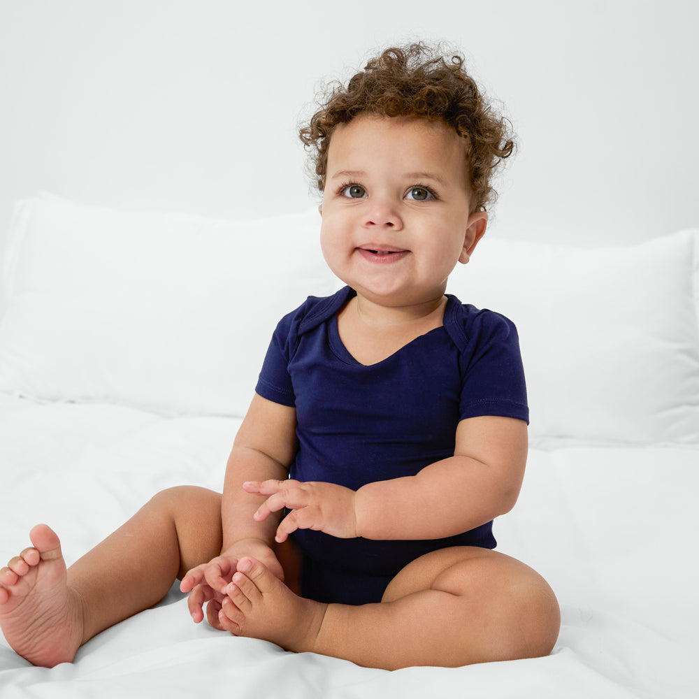 Sitting child wearing the Classic Navy Bodysuit