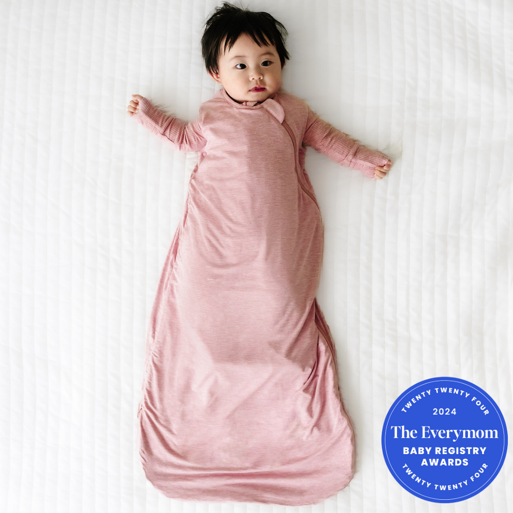 Child laying on a blanket wearing a Heather Mauve sleepy bag and matching zippy