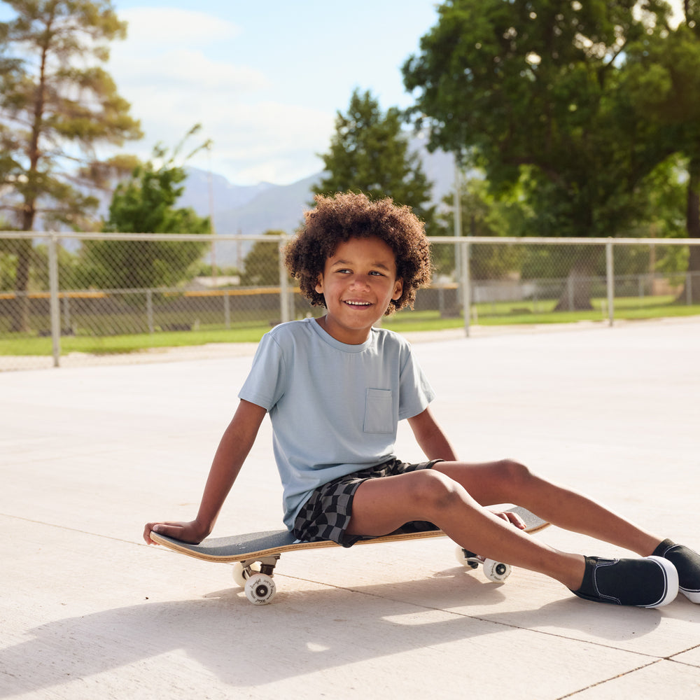 boy wearing fog tee shirt and monochrome checks shorts and fog pocket tee on a skateboard