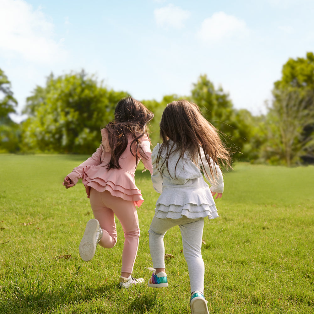 girl on the right is running and wearing a light heather gray peplum hoodie and matching leggings. girl on the left is wearing the same matching set in the color mauve blush