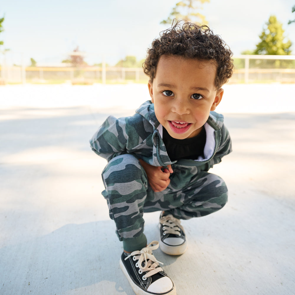 boy leaning over at camera wearing camo hoodie and matching joggers