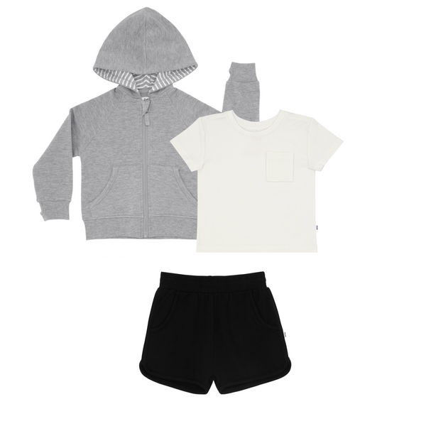 flat lay composite of a heather gray zip hoodie, soft white relaxed pocket tee, and black dolphin shorts