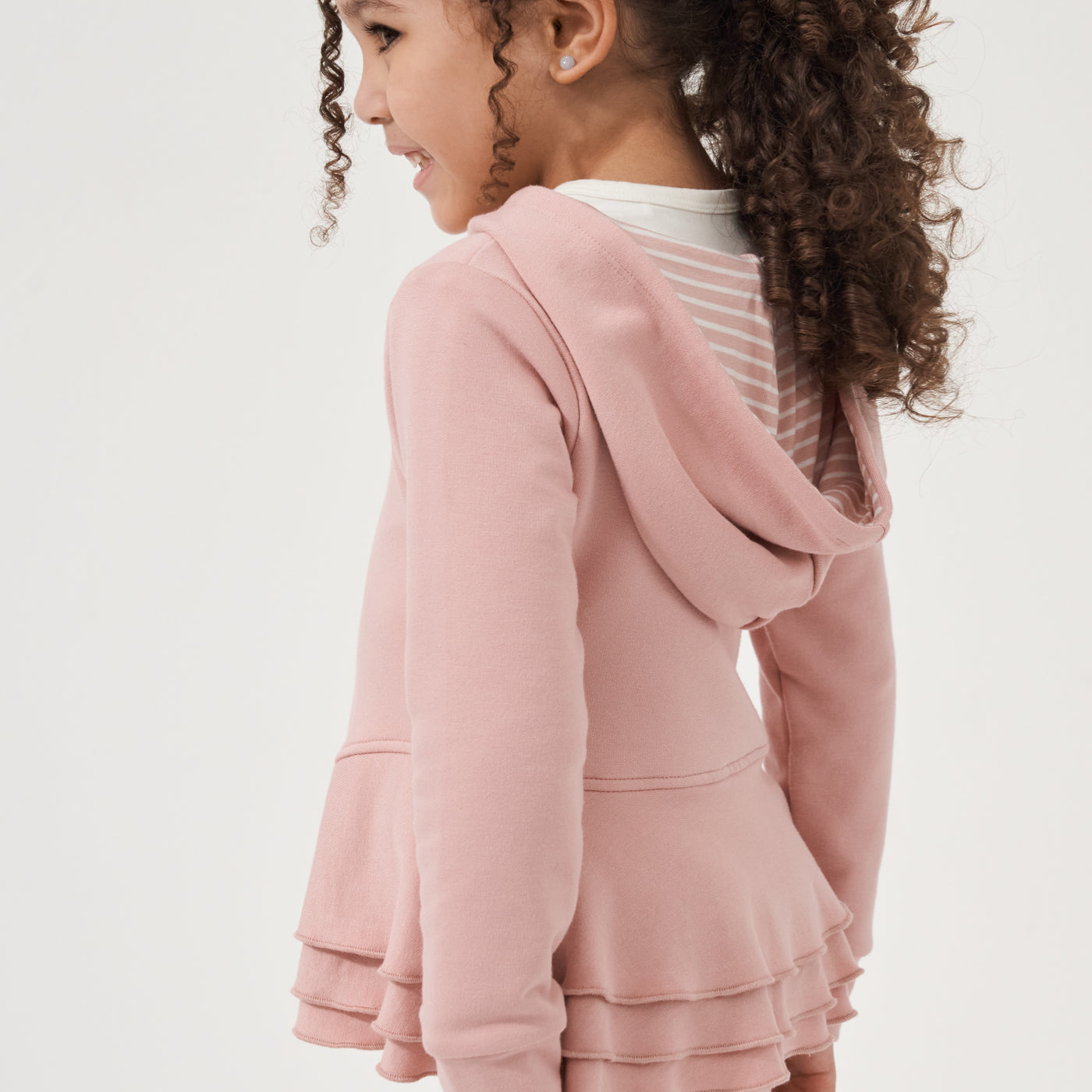 Close up profile view of a child wearing a Mauve Blush peplum hoodie