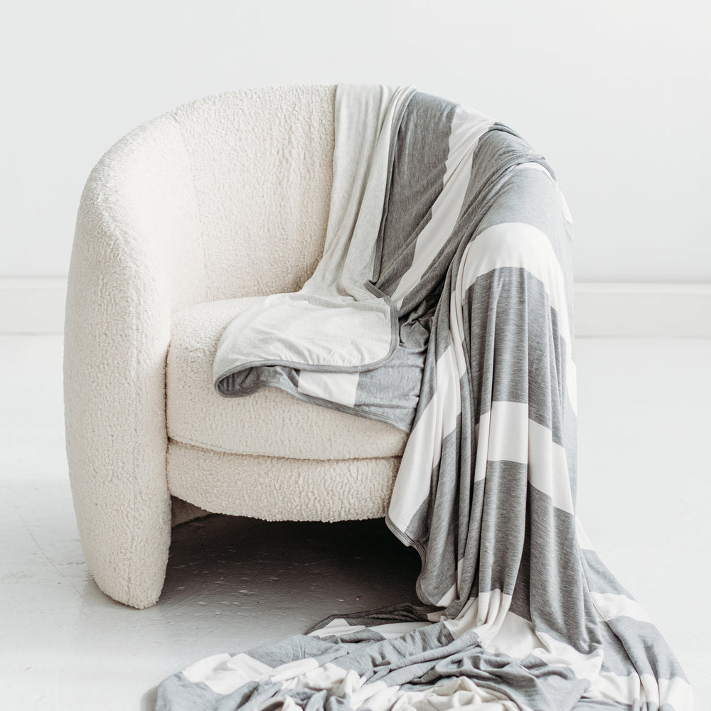 Heather Gray Stripe oversized bamboo blanket draped over the side of a chair.